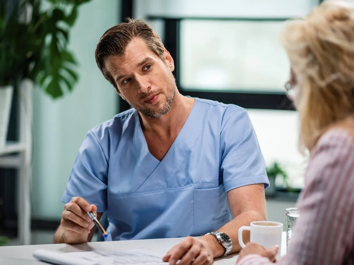 Arzt hört einer Patientin im Sprechzimmer zu