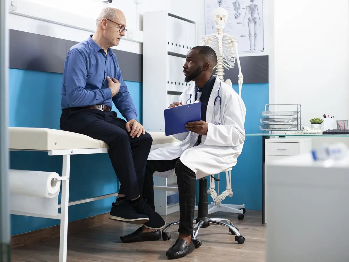 Patient sitzt auf der Untersuchungsliege und spricht mit seinem Arzt