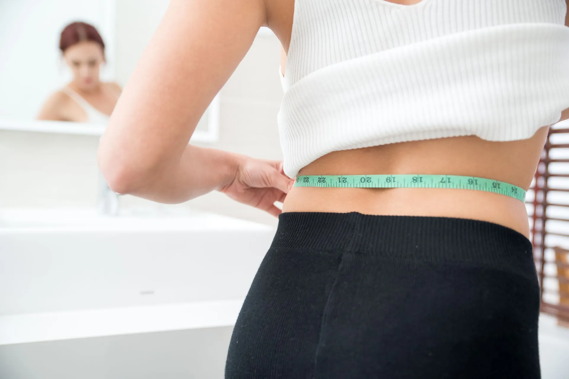 Frau misst mit einem Maßband ihre Taille